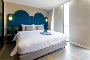 1 dormitorio con 1 cama blanca grande y cabecero azul en Benjarong Hotel Bangkok, en Ban Zong Katiam