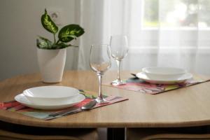 a wooden table with two plates and glasses on it at S1 Apartman in Szombathely