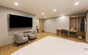慶州市にあるH Avenue Hotelの大型ベッド1台、テレビが備わる客室です。
