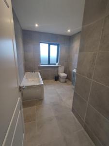 een badkamer met een bad, een toilet en een raam bij Stable Hill House in Killarney