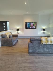 uma sala de estar com 2 sofás e uma televisão de ecrã plano em Stable Hill House em Killarney