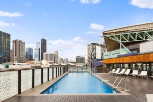 een zwembad op het dak van een gebouw met een stad bij Rooftop Pool 2BR Apt at Marvel Stadium with Free Parking in Melbourne