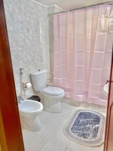 a bathroom with a toilet and a pink shower curtain at Great location apartment in Amman
