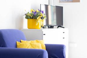 - un salon avec un canapé bleu et un pot de fleurs jaune dans l'établissement DEA APARTMENT, à Rapallo