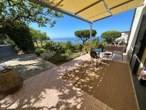 eine Terrasse mit einem Tisch, Stühlen und Meerblick in der Unterkunft La casa del Maestro in Pisciotta