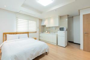 um quarto com uma cama branca e uma cozinha em Ocean Palade Hotel em Jeju