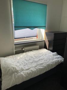 a bedroom with a bed and a window with a blue curtain at Nice room near airport in Copenhagen