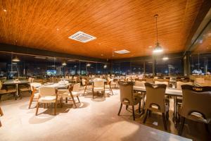 un ristorante con soffitti e tavoli in legno e sedie di The Bliss Hotel a Hubli