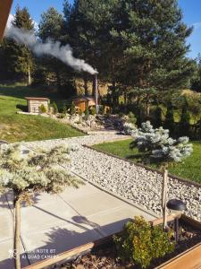 a garden with trees and a train in the distance at Domek Sielski Zakątek Pieniny in Szczawnica