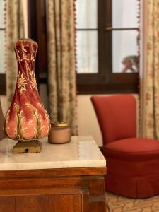 a red vase sitting on a table next to a chair at Casa Colonial El Indiano in Las Palmas de Gran Canaria
