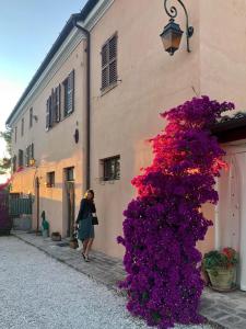 a woman walking down a street next to a building with purple flowers at APPARTAMENTO FONTEBELLA in Montemarciano