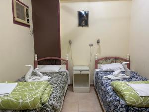 twee bedden in een kamer met zwanen erop bij Elphardous Hotel in Luxor