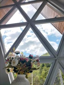 eine Vase voller Blumen vor einem Fenster in der Unterkunft Cabana All Seasons in Cavnic