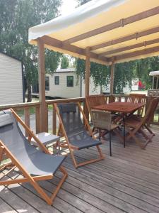 a wooden deck with a wooden table and chairs at Mobil-home La perle bleue in Ouistreham