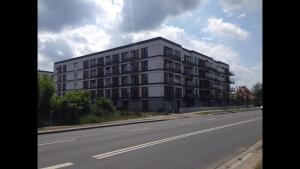 duży biały budynek przy drodze w obiekcie Apartament Nadwarciański w Poznaniu