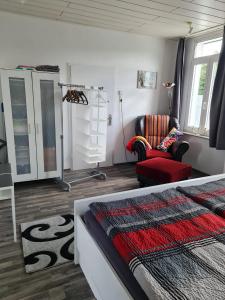 a bedroom with a bed and a living room with a chair at Drea's Ferienwohnung in Wermelskirchen