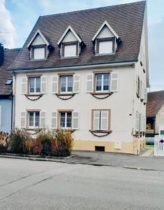 uma casa branca com janelas e um telhado em L'Envolée Alsacienne - Magnifique appartement en duplex em Ostheim