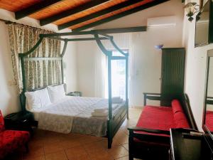 a bedroom with a canopy bed and a red couch at Blue Bay Beach Hotel in Koinyra