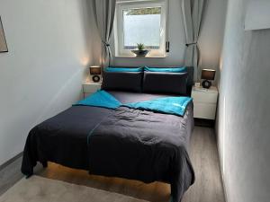 a bedroom with a bed with blue sheets and a window at Nollywood-Apartment in Rheinfelden