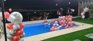 a bunch of red and white balloons next to a pool at סוויטה בכפר ירכא in Yarka