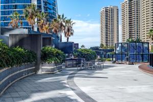 uma passarela com mesas e palmeiras numa cidade em No Parking - Converted Two Bedroom Apartment - Amazing Hinterland Views - Circle on Cavill - Wow Stay em Gold Coast