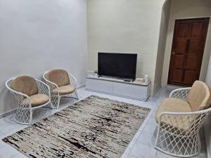 ein Wohnzimmer mit 3 Stühlen und einem TV in der Unterkunft SWEET PARADISE HOMESTAY in Parit Raja