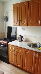 - une cuisine avec des placards en bois, un évier et une cuisinière dans l'établissement Роза, à Bishkek