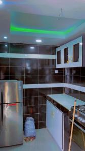 W kuchni znajduje się lodówka ze stali nierdzewnej, a ściany wyłożone są czarnymi kafelkami. w obiekcie Meerah apartments & Hotels 
