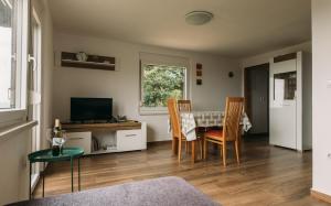 Apartma Hiša na Ravnah في Pišece: غرفة معيشة مع طاولة وكراسي وتلفزيون