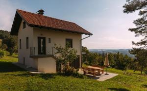 una pequeña casa blanca con un banco y una mesa en Apartma Hiša na Ravnah, en Pišece