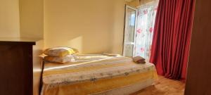 a bedroom with a bed and a window with red curtains at Chaika Sea Apartment in Varna City