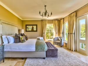 Schlafzimmer mit einem Bett, einem Stuhl und Fenstern in der Unterkunft Devonport House - Constantia in Kapstadt