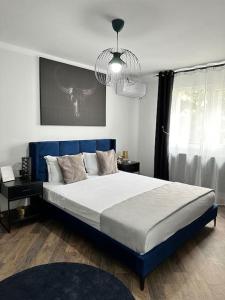 a bedroom with a large bed and a chandelier at Priveé Residence in Caransebeş