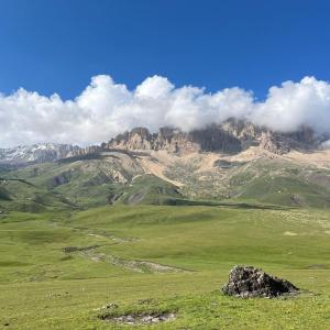 a green field with a mountain in the background at Mountain house in Xınalıq