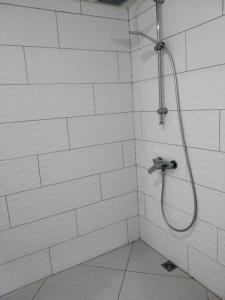 La salle de bains est pourvue d'une douche avec un tuyau et de carrelage blanc. dans l'établissement Chalet Ohana, airport family house, à Fa'a'ā