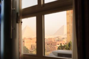 einen Blick auf die Pyramiden aus einem Fenster eines Gebäudes in der Unterkunft King Khafren View INN in Kairo
