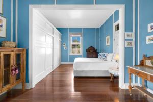 a bedroom with blue walls and a white bed at Pacific Lodge in Hyams Beach