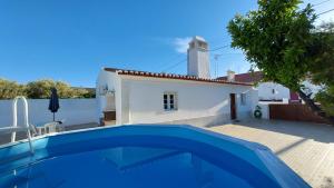 a villa with a swimming pool in front of a house at Monte do Ti'Mota in São Lourenço de Mamporcão