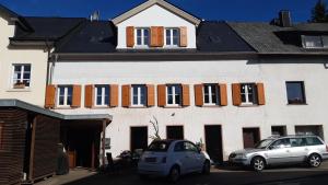 two cars parked in front of a white building at Ales Ursula Sokolowski in Zerf