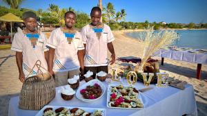 two men standing in front of a table with food at Três Sereias - 3 Mermaids in Govuro