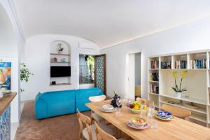 a dining room with a table and a blue couch at Casa Luma, il sogno di Positano! in Positano