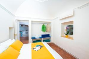 a room with a white bed and a yellow couch at Casa Luma, il sogno di Positano! in Positano