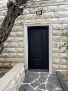 una puerta negra en un edificio de piedra con un árbol en A cozy place with free parking and spacious garden, 