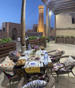 a table with chairs and plates of food and a lighthouse at Art Suzani National House Hotel in Bukhara