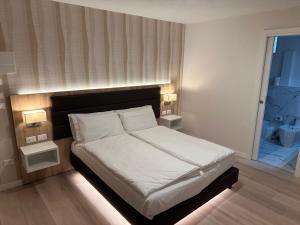 una camera da letto con un letto con lenzuola bianche e una finestra di Hotel Derby S a Lido di Jesolo