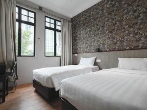 a hotel room with two beds and two windows at The Noble Hotel in Singapore