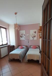 2 Betten in einem Zimmer mit rosa Wänden in der Unterkunft Casa Vacanze Le tre Sorelle in Torre Pellice