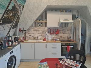 a kitchen with white cabinets and a brick wall at LA TOURELLE in Morlaix