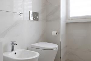 La salle de bains blanche est pourvue de toilettes et d'un lavabo. dans l'établissement Duomo Home - 6 stops from Duomo, 5min from central station, AC, Netflix,, à Milan