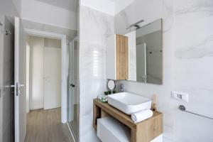 La salle de bains blanche est pourvue d'un lavabo et d'un miroir. dans l'établissement Duomo Home - 6 stops from Duomo, 5min from central station, AC, Netflix,, à Milan